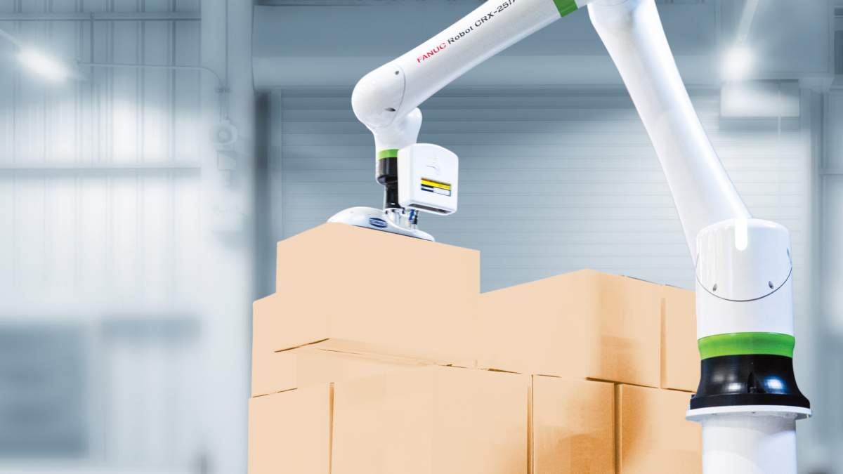 A robotic arm is stacking cardboard boxes in a warehouse with a bright, industrial interior. The background shows metal structures and large doors.
