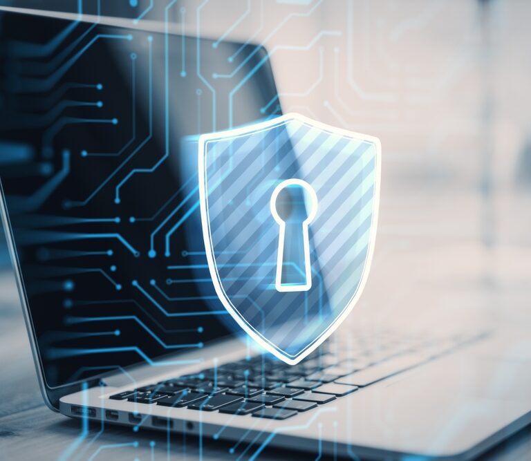 A laptop with a glowing digital shield featuring a keyhole symbol is displayed in the foreground, representing cybersecurity and online data protection for Autonomous Mobile Robots. Blue circuit lines are overlaid on the image.