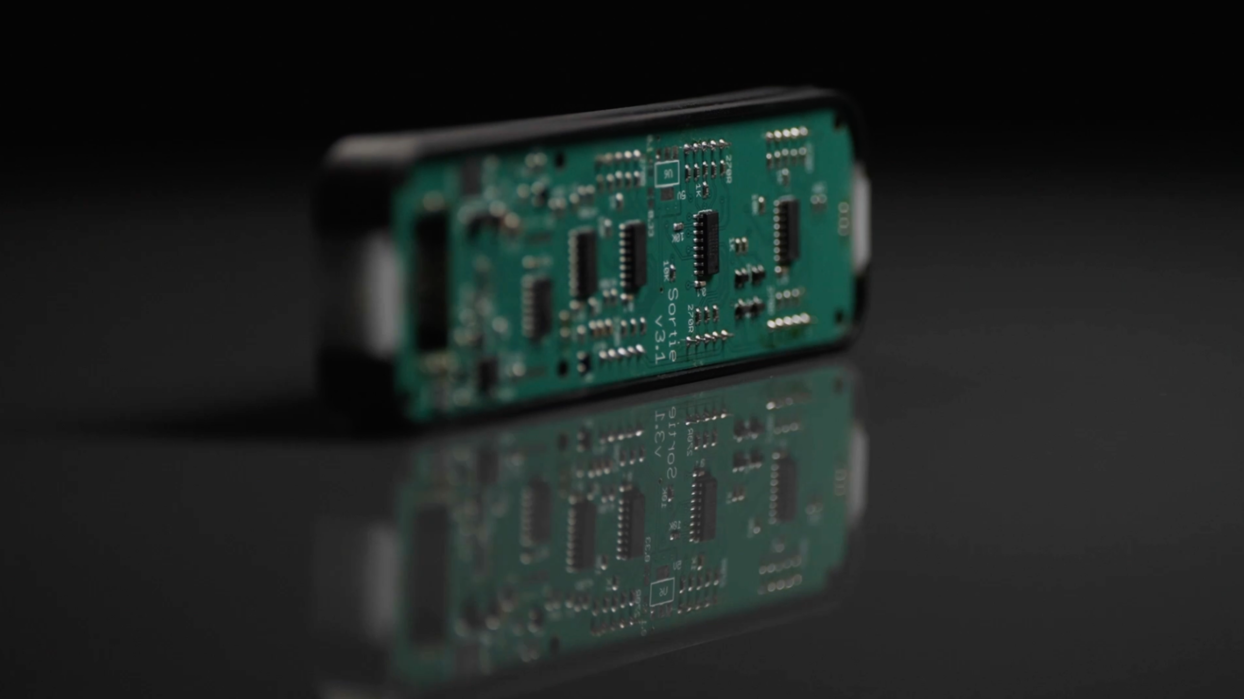 A close-up of a green printed circuit board with electronic components, essential for network management, stands upright on a reflective black surface, its reflection visible below.