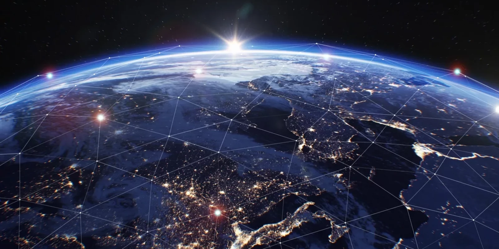 View of Earth from space at sunrise, with illuminated cities and network lines showing global connectivity. The horizon glows with sunlight, and the planets surface features continents and scattered clouds.