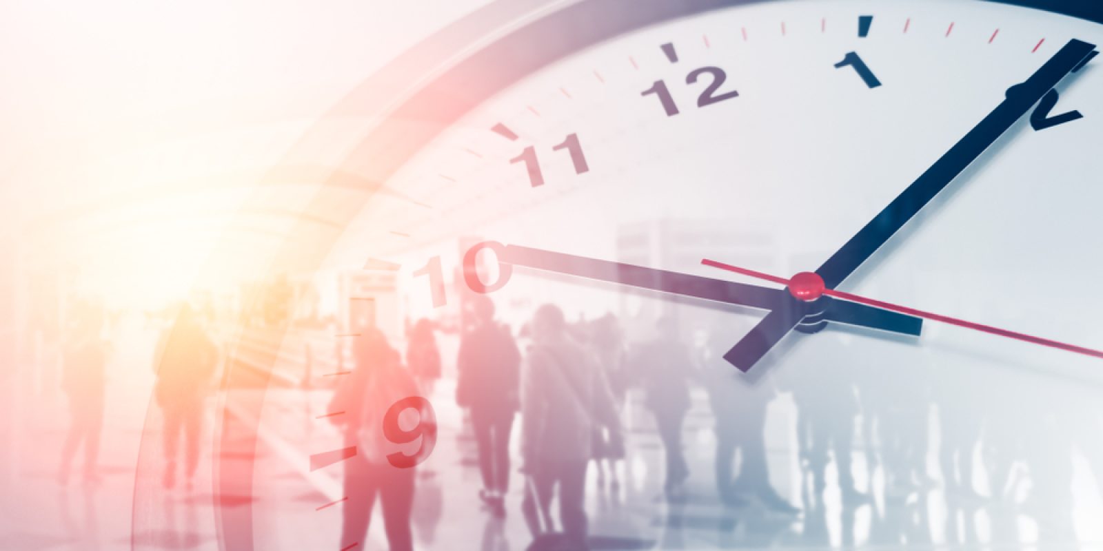 A close-up of a clock face showing the time as 10:09, with a blurred background of people walking in a brightly lit indoor space, creating a sense of motion and passing time.
