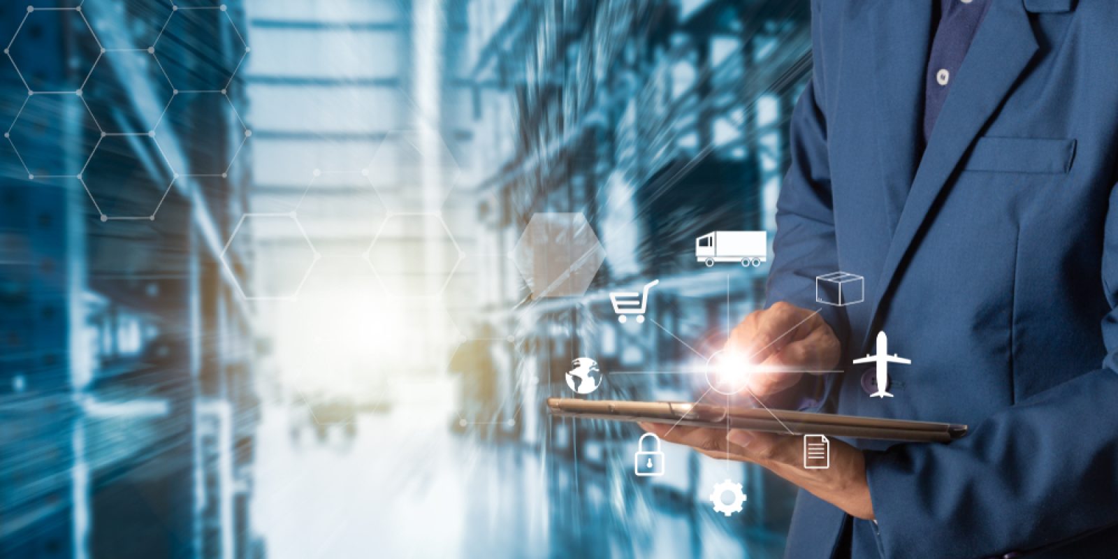 A person in a suit uses a tablet, with logistics and supply chain icons like a truck, cart, box, airplane, and lock overlaid. The background shows a blurred warehouse or industrial setting.