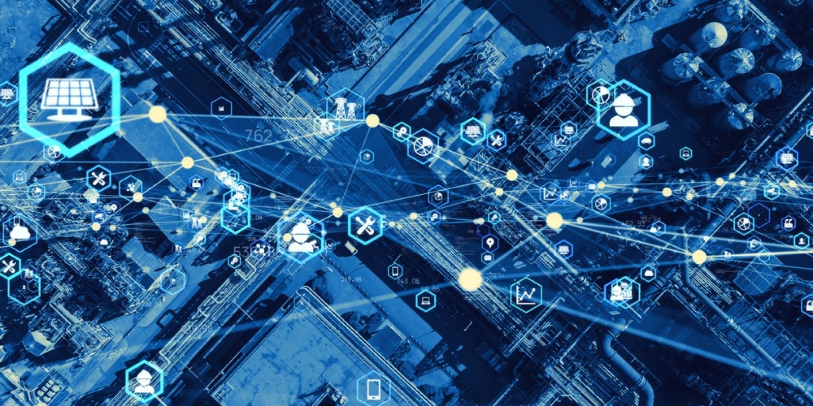 Aerial view of an industrial facility overlaid with digital icons and network lines, symbolizing data connectivity, supply chain optimization, smart technology, and industrial automation. The color scheme is predominantly blue.